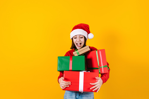 Portrait of Latin child girl holding Christmas gift box on a yellow background in Mexico latin america