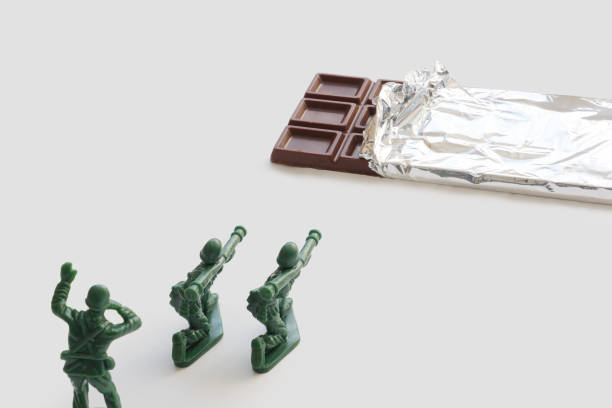 istock Miniature soldiers trying to destroy chocolate bar 1353341104