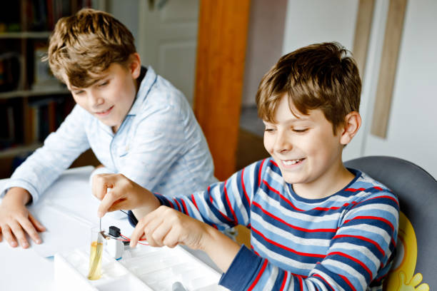 istock Two kids boys doing electric physical experiment as homework at home. Children study electricity. Education. Best friends, brothers learning physics. 1353341509
