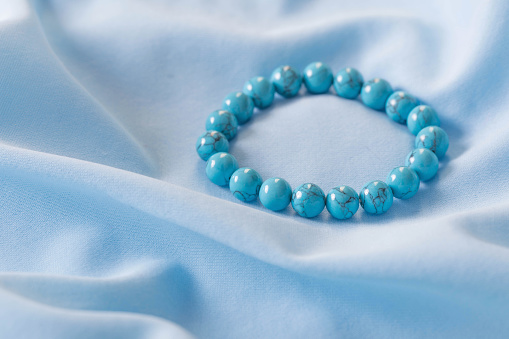 turquoise bracelet made of natural stones on blue silk  fabric
