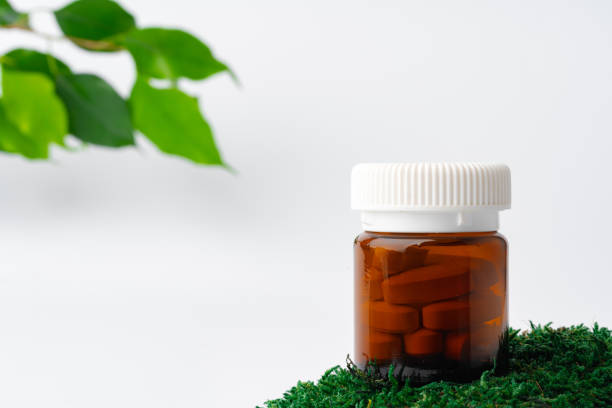 istock Brown glass bottle with pills on moss, dietary supplement 1353347097