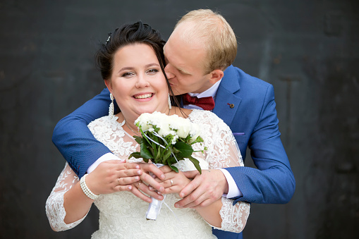 Wedding bouquet with daisies and roses held by a bride.