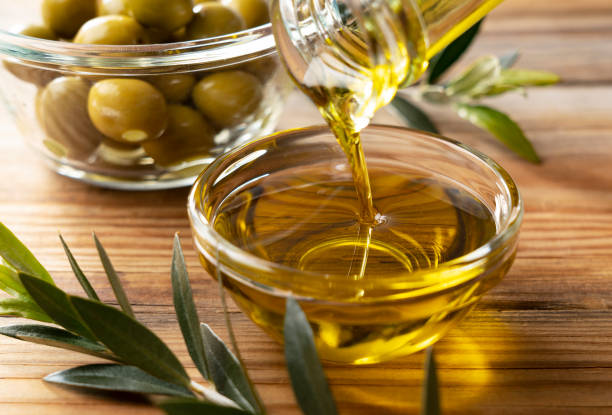 aceite de oliva en un recipiente de vidrio sobre un fondo de madera - aceite de oliva fotografías e imágenes de stock