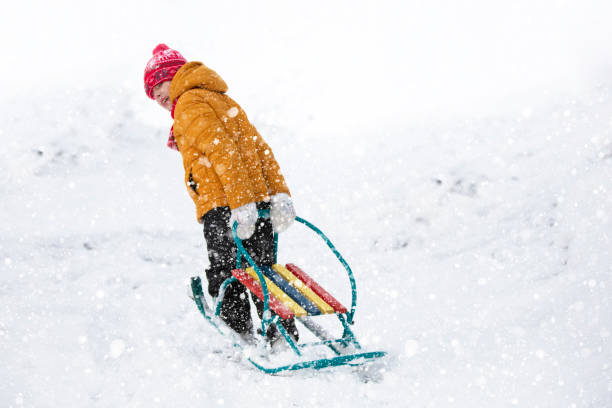 istock A little boy pulls a sled up a snowy mountain. Child on a winter day. 1353349304