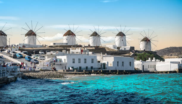 Traditional Greek windmills on Mykonos Island, Greece. Panoramic landscape with 6 old whitewashed windmills along the coastline at the popular and touristic town of Mykonos Island in Greece. Turquoise colored sea, blue sky, some clouds on a beautiful summer vacation day. cyclades islands stock pictures, royalty-free photos & images