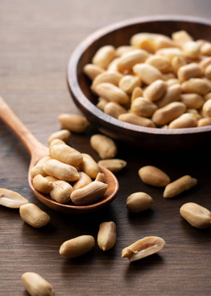 istock Peanuts in a wooden bowl on a wooden table. 1353351969