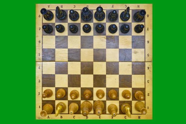 istock Retro chessboard with placed old pieces in the starting position, isolated on a green chromakey 1353353021