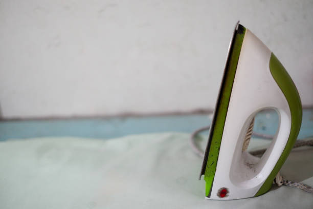 Iron on Ironing Board Against a White Wall with Copy Space closeup.