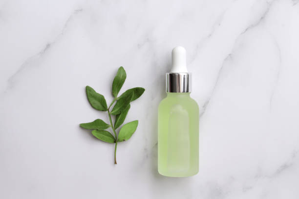 istock Glass bottle with serum and leaves on marble background 1353353633