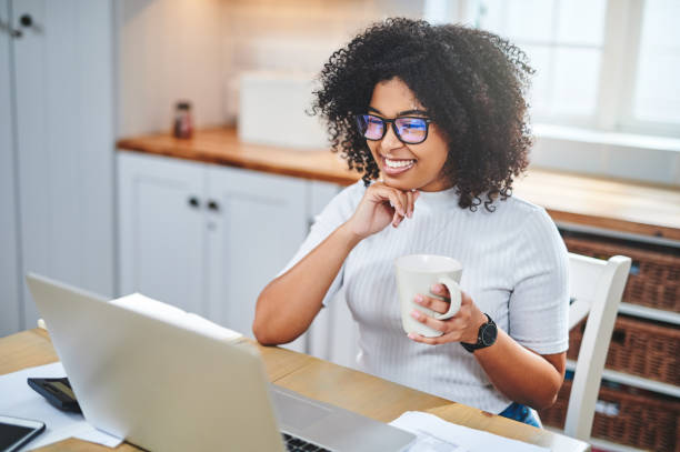 istock Shot of a young woman using a laptop and having coffee while working from home 1353356082