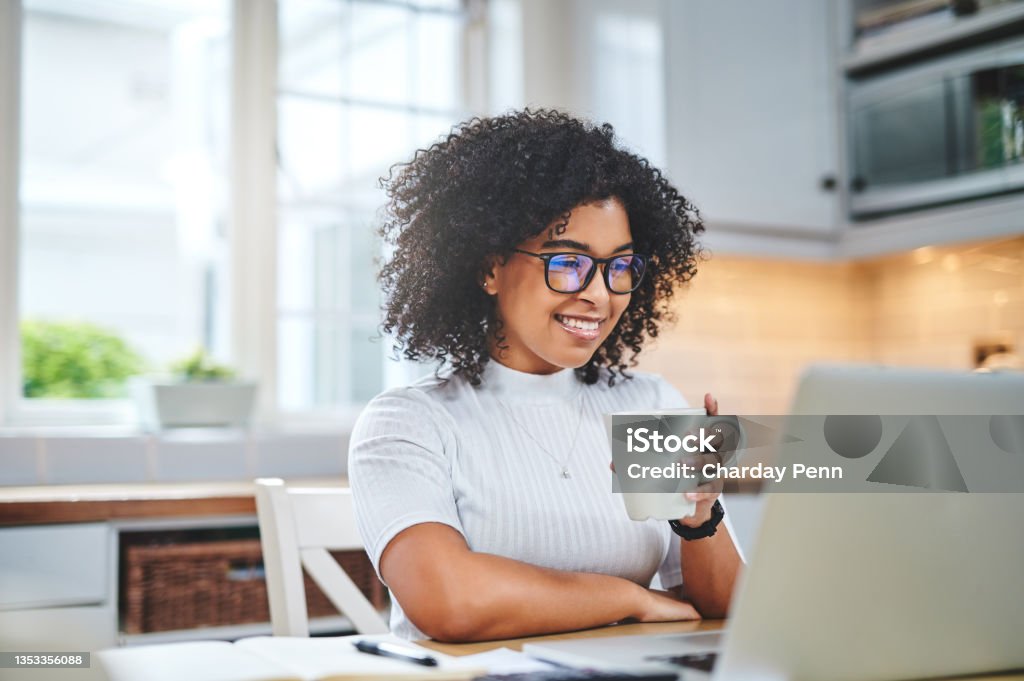 Shot of a young woman using a laptop and having coffee while working from Look at the stats on this baby Education Training Class Stock Photo