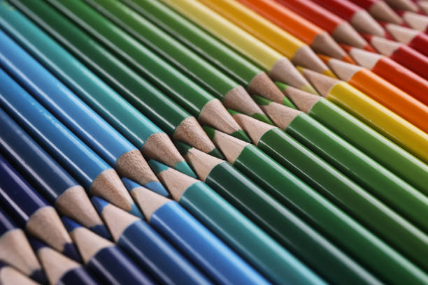 Close-up of colourful childrens drawing pencils pointing one another in line. Same colours fit each other, perfectionist vision. Anti-stress, art concept
