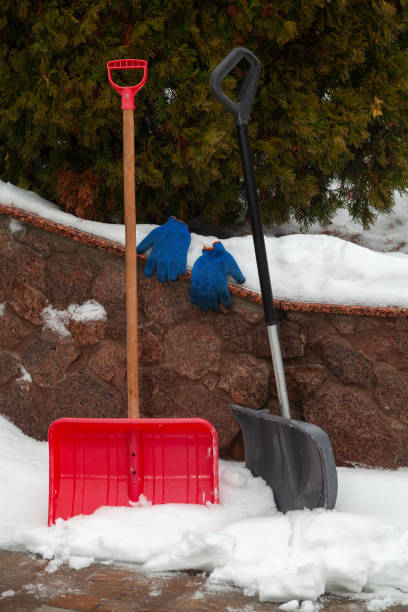 istock Two plastic snow shovels stand in front of  fence 1353357260