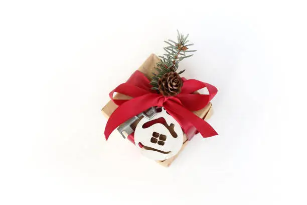 box with a red bow, key and house decorated with a fir branch with a pine cone top view