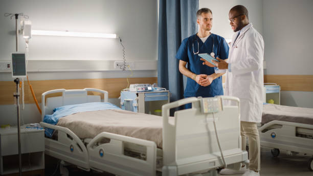 istock Hospital Ward: Black Doctor Talks With Professional Caucasian Head Nurse or Surgeon, They Use Digital tablet Computer. Diverse Team of Health Care Specialists Discussing Test Result in Modern Clinic 1353357568