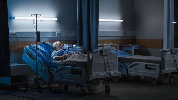 ala hospitalar: retrato de idoso usando máscara de oxigênio descansando na cama, lutando para se recuperar após covid-19, doença, doença, cirurgia. velho lutando por sua vida. tiro trágico azul escuro - bed - fotografias e filmes do acervo