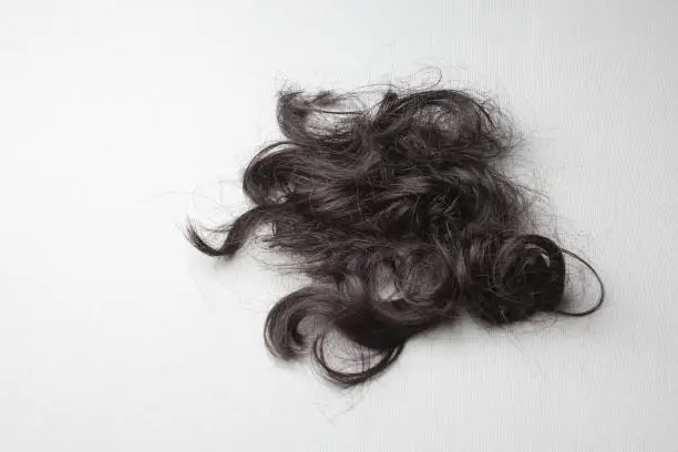 Photo of A lock of black hair on a white surface