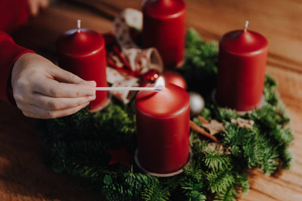 Human hand lighting the first candle of Advent Wreath on the first Advent Sunday counting four weeks untill Christmas. Lighting the first candle of Advent Wreath on the first Advent Sunday counting four weeks till Christmas. Old swiss tradition in December to celebrate Advent time. advent candle wreath adventskranz stock pictures, royalty-free photos & images