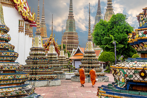 Monks walking alongside stupas at Wat Pho Buddhist Temple in downtown Bangkok Thailand