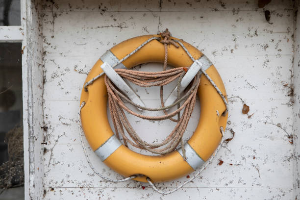 istock Orange coloured lifebuoy fixed to a dirty white box on a wall 1353362237
