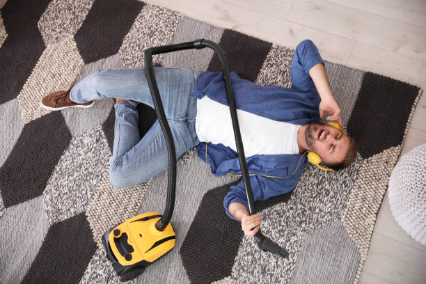 istock Young man having fun while vacuuming at home, above view 1353362710