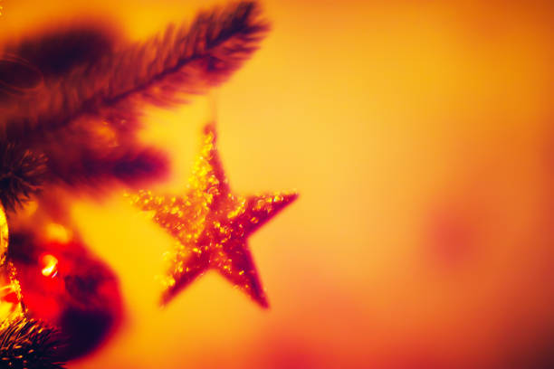 Blurred background with Christmas tree branch and glittering star shining with bokeh lights.