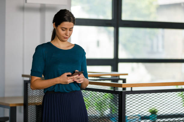 istock Young businesswoman dialing a number on smart phone while walking through the office 1353363143