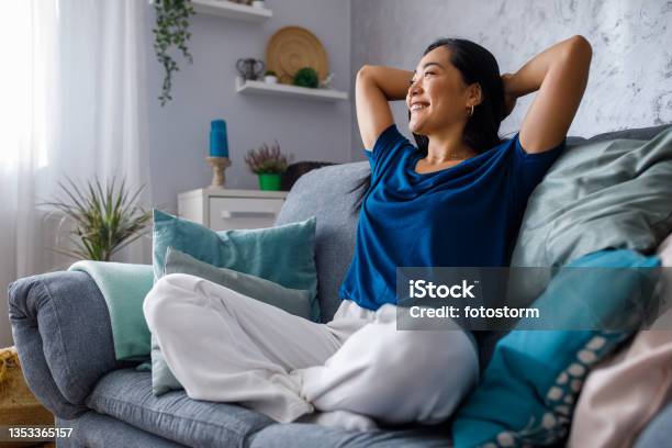 Copy Space Shot Of Young Woman Lounging On Sofa With Hands Behind Head And Daydreaming Stock Photo - Download Image Now