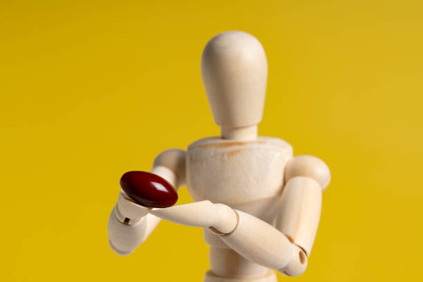 istock Wooden manikin with pills on yellow background. 1353365320