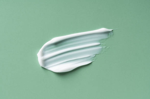 Green White cosmetic cream on green background. Green White cosmetic cream on green background. Cosmetic BB make up swatch. Drop of liquid foundation strokes. makeup swipes stock pictures, royalty-free photos & images