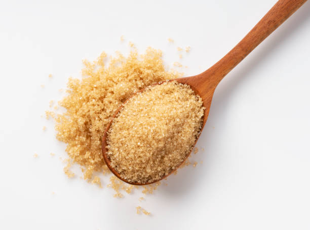 Wooden spoon and brown sugar on a white background.