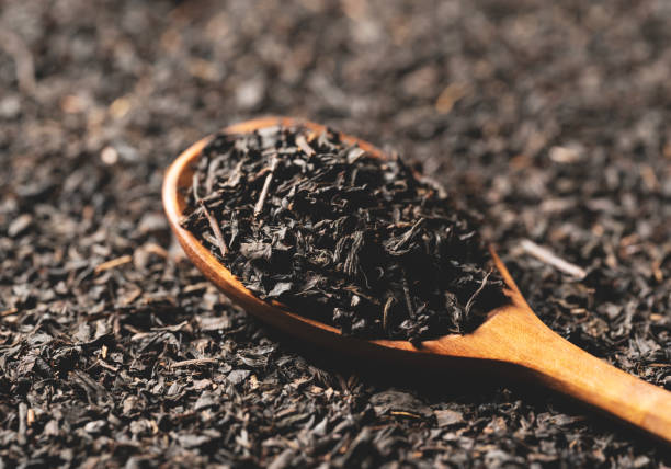 Background with tea leaves and a wooden spoon throughout the screen. Background with tea leaves and a wooden spoon for the entire screen. Close-up. black tea stock pictures, royalty-free photos & images