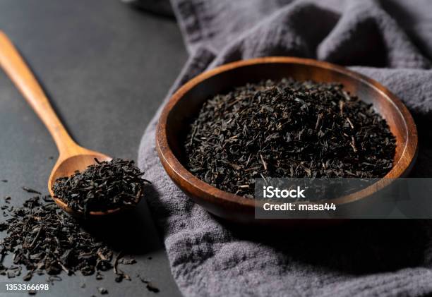 Tea Leaves In A Wooden Plate And Spoon On A Black Background Stock Photo - Download Image Now