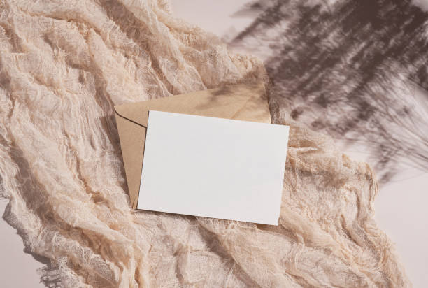istock Summer wedding stationery mockup. Beige background with plain greeting cards, invitations and gauze fabric. Natural light and shadow overlay. Flat lay, top view. 1353366764