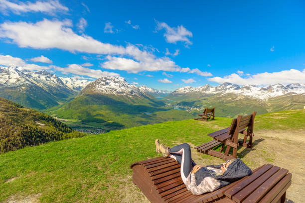 woman on top of Muottas Muragl station Woman resting on a bench on top of Muottas Muragl station of the famous funicular railway in Switzerland. Popular location for mountain excursions in Graubunden canton of Switzerland. samedan stock pictures, royalty-free photos & images
