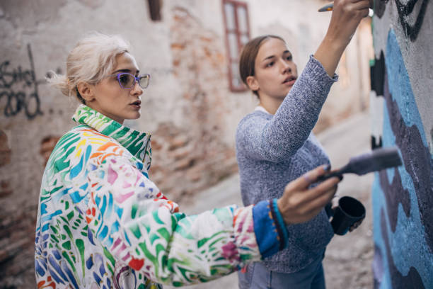 istock Female artists painting on building wall 1353369682