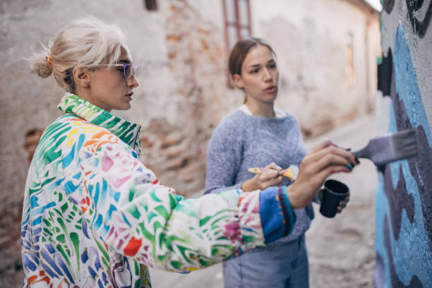 istock Female artists painting on building wall 1353369703