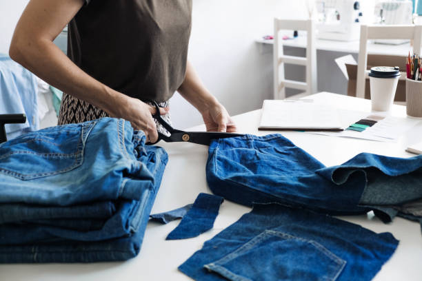 istock Denim Upcycling Ideas, Using Old Jeans, Repurposing Jeans, Reusing Old Jeans, Upcycle Stuff. Woman seamstress cut and repair old blue jeans in sewing studio. 1353369792
