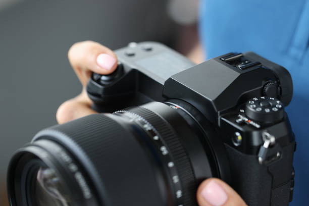 istock Woman holding modern camera for photos, close-up 1353369863
