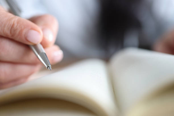 istock Woman's hand holding a pen near notepad, close-up 1353369870