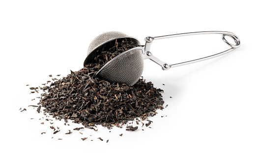 Earl Grey tea leaves and stainless steel tea strainer on white background