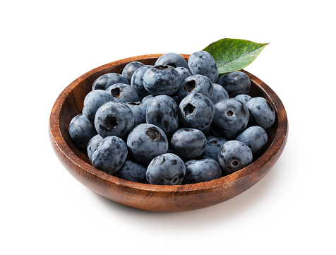 Blueberries in a wooden bowl set against a white background.