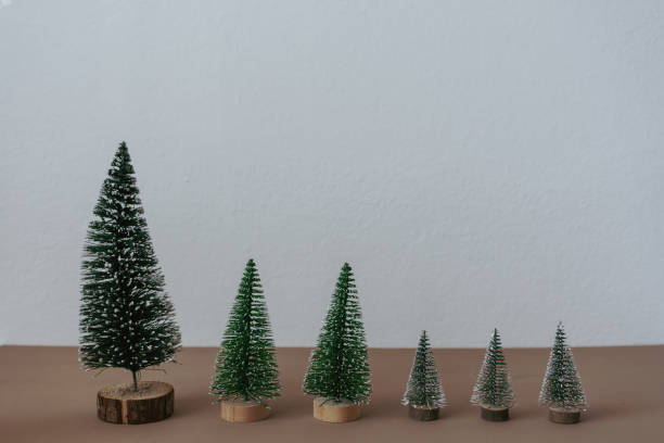 istock Different big artificial Christmas trees on a brown wooden table 1353371330