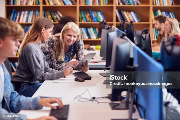 Female University Or College Student Working At Computer In Library Being Helped By Tutor Stock Photo - Download Image Now