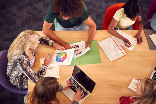 istock Overhead Shot Of University Or College Students Sitting Around Table With Tutor In Lesson 1353372111