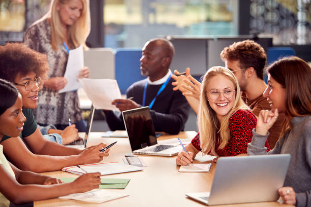 istock University Or College Students Sitting Around Table With Tutor Collaborating In Seminar On Laptop 1353372682
