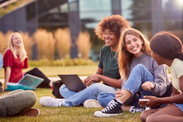istock Group Of University Or College Students Sit On Grass Outdoors On Campus Talking And Working 1353372804