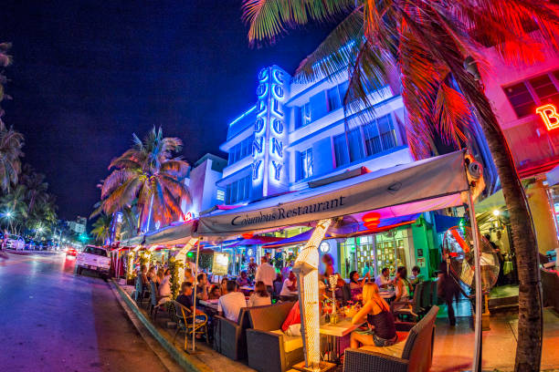 les gens profitent de la soirée dans le restaurant columbus à côté de la célèbre colonie d’hôtels art déco à ocean drive, miami - colony photos et images de collection