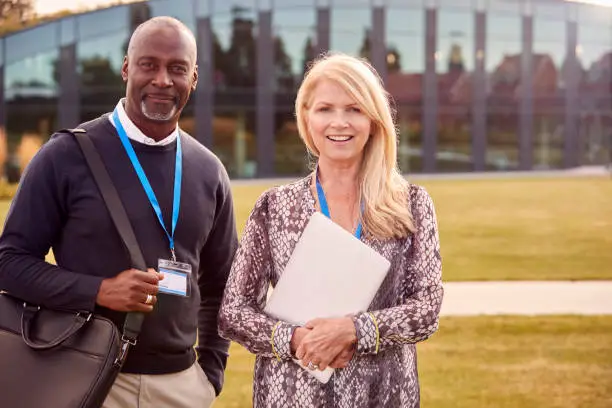 Photo of Portrait Of Male And Female University Or College Tutor Outdoors With Campus Building In Background