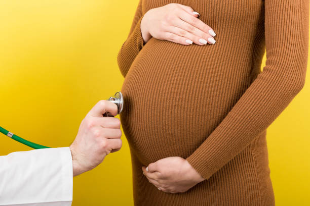 zbliżenie lekarza badającego kobietę w ciąży na kolorowym tle - healthcare and medicine bed patience human pregnancy zdjęcia i obrazy z banku zdjęć